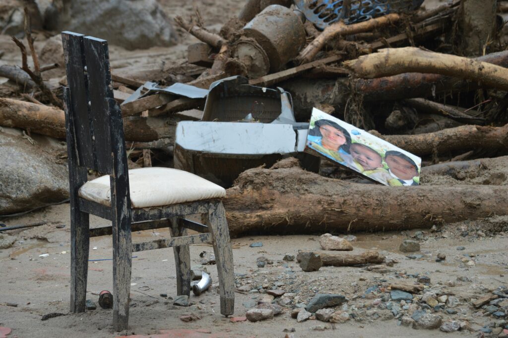 Destruction in Mocoa, Colombia shows a damaged chair amidst debris and rubble, highlighting natural disaster's impact.